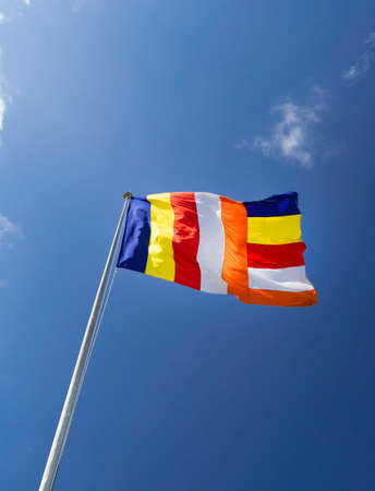 Waving colorful Buddhist Sri Lanlan Flag in cloudy blue sky background