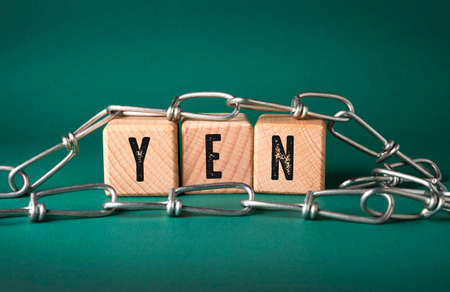 The word YEN is written on wooden cubes on a beautiful green background with chain.
