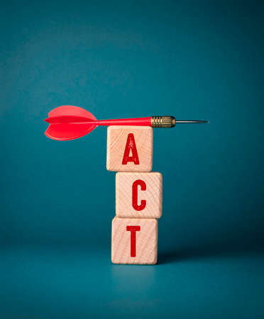 The word Act is written on wooden cubes next to a dart.の写真素材