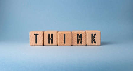 The word Think is written on wooden cubes on a blue background.の写真素材