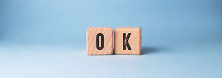 The word OK is written on wooden cubes on a blue background.の写真素材