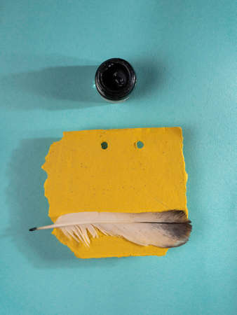 Quill and yellow paper on blue background. Top view.の写真素材