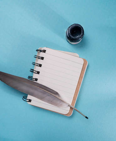 Notebook with pen and ink bottle on blue background, top viewの写真素材