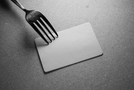 Blank card and fork on grey background, closeup. Space for text