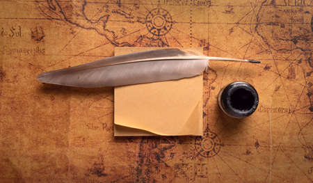 Feather pen and inkwell on old map, top view.の写真素材