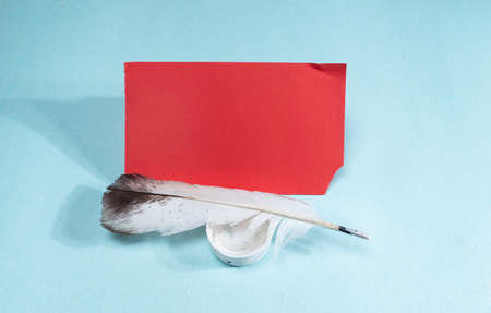 A quill and a red sheet of paper on a blue backgroundの写真素材
