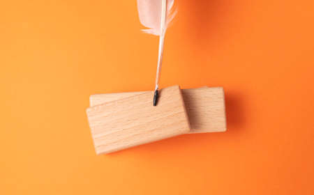 A quill and a wooden diary on a bright orange background.の写真素材