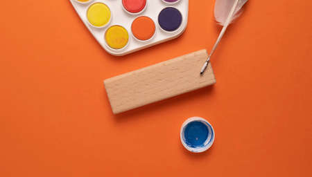Top view of watercolor paints, brushes and palette on orange backgroundの写真素材