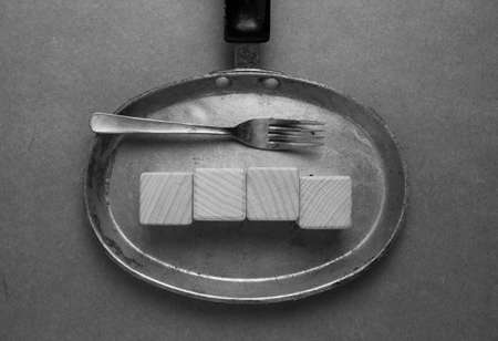 Wooden cubes on a frying pan and a fork. Black and white photo.の写真素材