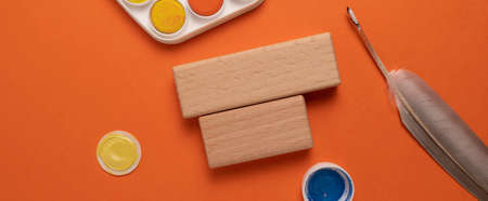 top view of wooden blocks and paints on orange background, flat layの写真素材