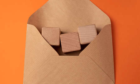 Brown envelope with wooden cubes on an orange background. Copy space.の写真素材