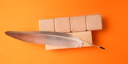 Wooden cubes with feather and quill on orange background, top viewの写真素材