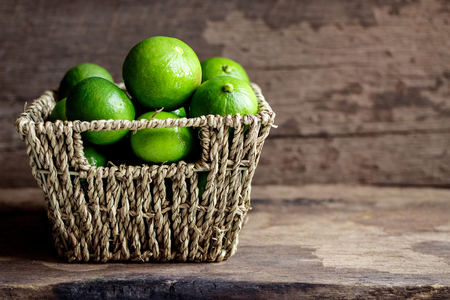Fresh limes in the basket on a wooden backgroundの写真素材