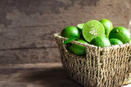 Fresh limes in the basket on a wooden backgroundの写真素材