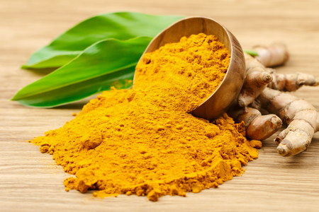 Turmeric powder in wooden bowls on wooden tableの写真素材