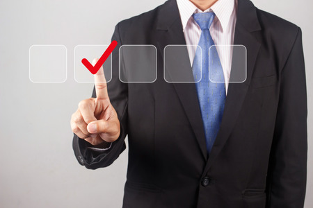 Businessman hand checking the checklist boxes on gray backgroundの写真素材