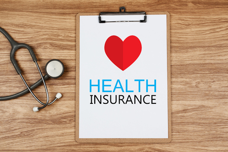 Clipboard with text Health INSURANCE and paper heart with stethoscope on wooden desk, Healthcare and Medical Conceptの写真素材