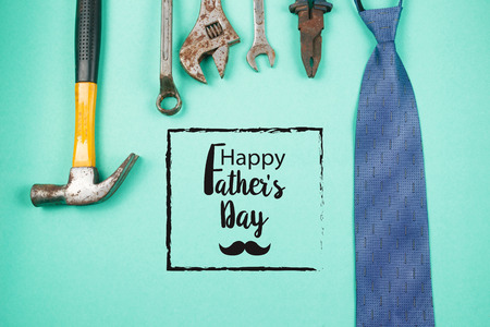 Happy Father's Day text with old rusty tools and ties on green paper background
