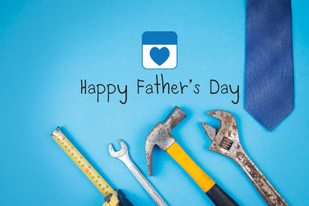 Happy Father's Day text with old rusty tools and tie on blue paper backgroundの写真素材