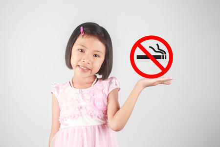 Cute little girl holding no smoking sign on gray backgroundの写真素材