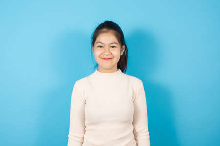 Portrait of Asian teenager wearing light pink sweater excited for success with arms raised isolated...