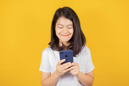 Portrait of smiling Asian teenager wears white t-shirt she is using mobile phone or smartphone...