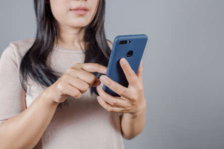 Portrait of Asian woman with long dark hair wears nude t-shirt finds out about her husband betrayal by spying on his phone, secretly check, pick up informationの写真素材