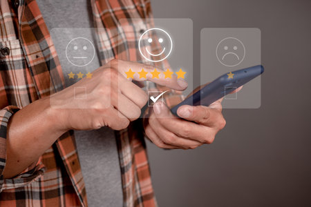 Man choosing happy icon on virtual touch screen at smartphone, satisfaction survey. mental health assessment. world mental health day conceptの写真素材