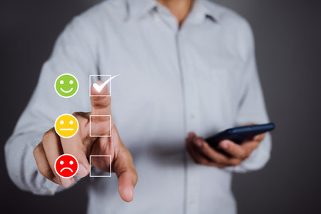 Man choosing green happy icon on virtual touch screen at smartphone, satisfaction survey. mental health assessment. world mental health day conceptの写真素材
