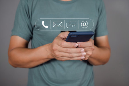 Man holding smart mobile phones and touching with call phone, email, chat message icons and address.の写真素材