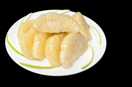 Slices of pomelo fruit on white plate on black Backgroundの写真素材