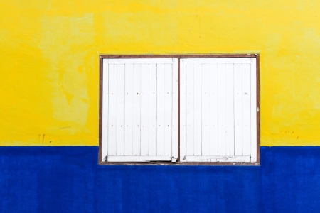 old wooden window on colorful yellow and blue wall の写真素材