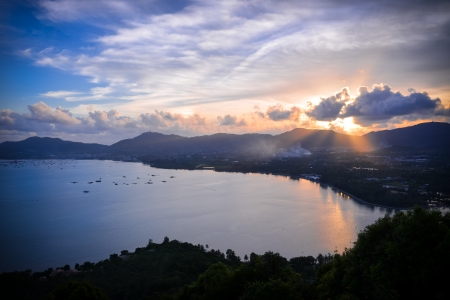 Dramatic sunset on the sea, sun light pass through cloud over mountain, phuket Thailand の写真素材