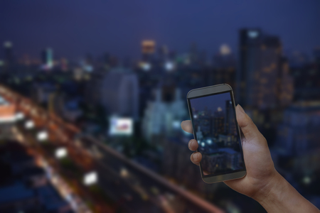 Phone on hand transparent to city and town background, concept of modern life cellular connectivity unique in townの写真素材