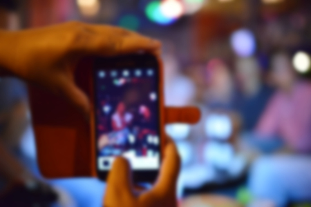 blurred smartphone taking a photo in night partyの写真素材