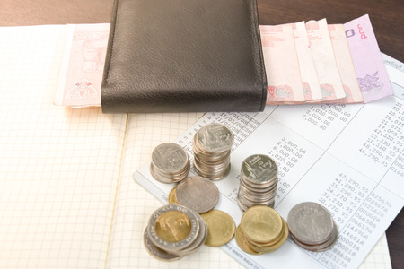 Thai money and bank saving account book on wooden table, money savings concept
