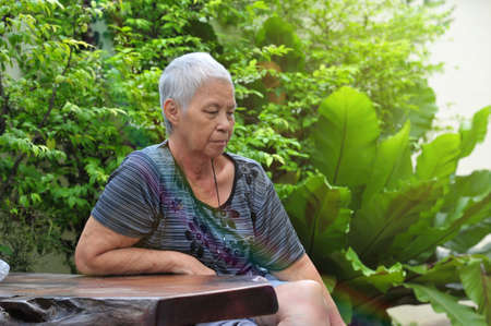 old asian lady sitting in garden