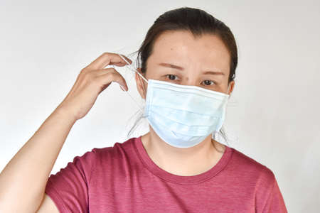 Asian woman removing a mask from her face