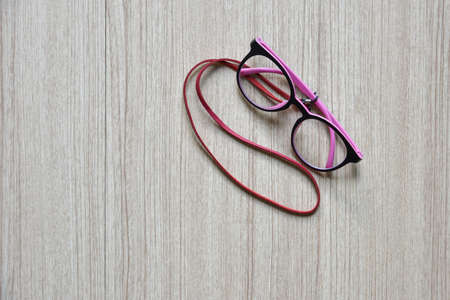 Clear Eyeglasses, Glasses pink and black Frame Vintage Style with neck strap on Wood Backgroundの写真素材