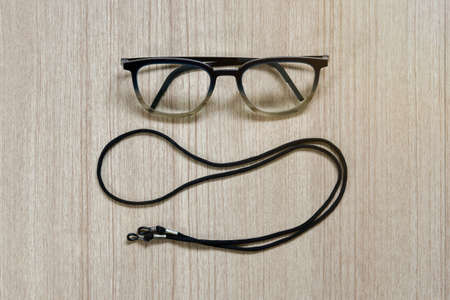Clear eyeglasses, Glasses transparent dark blue frame with black eyeglasses strap on a wooden backgroundの写真素材