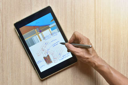 a tablet showing hand sketch of architectural drawing design detail with digital pens on wood table, the concept of new technology for working of tablet with digital penの写真素材