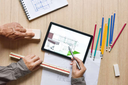 a tablet showing architectural drawing design detail selection of building color with digital pens on wood table, the concept of new technology for working of tablet with digital penの写真素材
