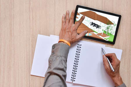 a tablet showing hand sketch of architectural drawing design detail with digital pens on wood table, the concept of new technology for working of tablet with digital penの写真素材