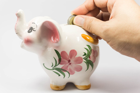 Putting coin into elephant bankの写真素材