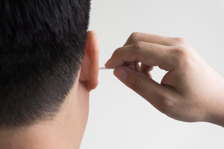 man cleaning ear with cotton budの写真素材