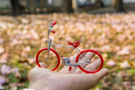 Red Bicycle on hand with Beautiful pink Flower background.の写真素材