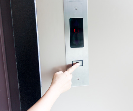Woman hand pressing the button in the elevator.