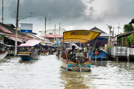 SAMUT SONGKHRAM, THAILAND - JULY 22, 2017 : AMPHAWA FLOATING MARKET, on weekends, the Amphawa Canal brims with boats loaded with drinks like O-Liang (Thai iced black coffee) and food such as fried sea mussels, noodles, and sweets. Bank-side wheelbarrows aのeditorial素材