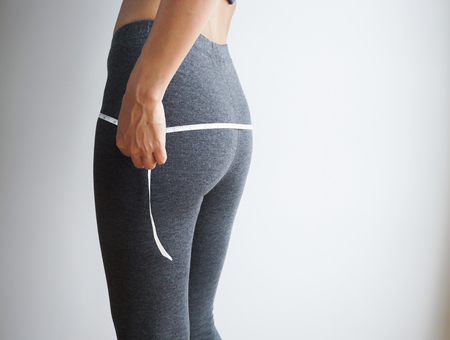 Slim body of asian woman with a measuring tape on white background.の写真素材