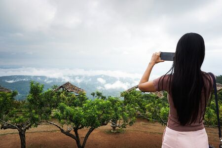 Woman taking photo on mobile phone, landmark in Chiang Mai, Thailand.の写真素材